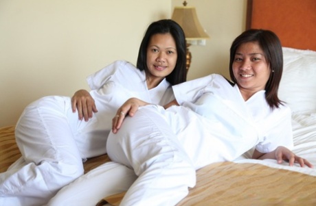 In their white uniforms, Joanna and Joy, nurses from flamboyant Filipino nations, pose for a picture on the bed.