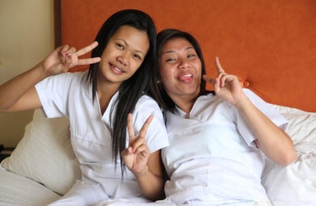 The white uniformed nurses Joanna and Joy, who are lusty Filipinos, take a photo on the bed.