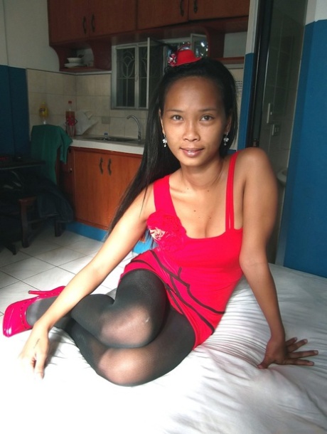 Trisha Mae, a slim Asian female who wears a red dress, exposes her pussy on a bed.