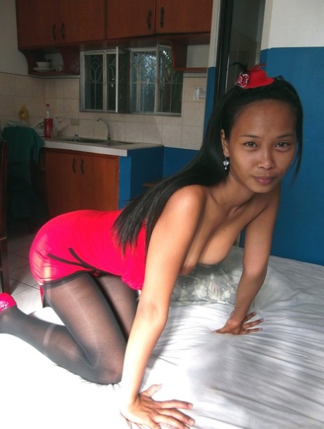 Trisha Mae, a thin Asian girl who shows her pussy, exposes her red dress while lying on the bed.