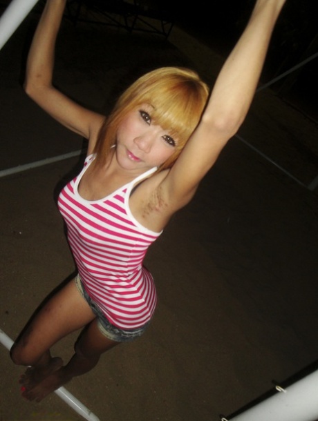 As a skinny blonde ladyboy, Nan wears high-heeled shoes and displays her attractive curves and buttocks.