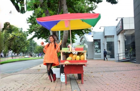 Красивый колумбийский продавец фруктов провокационно жестикулирует бананом