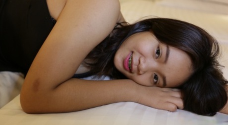 The charming girl from Thailand is seen wearing braces and flip flops as she lounges in her short pants, blouse, and shirt.