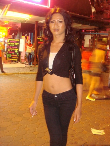 A tourist takes pictures of ladyboys while strolling on the night streets.