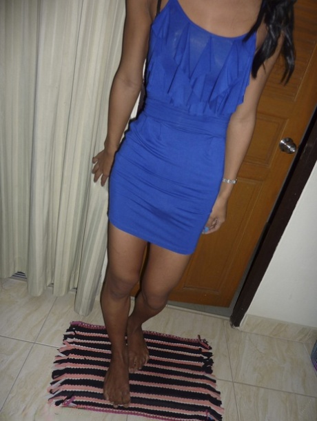 In a dark-skinned ladyboy's bedroom, he is seen in a blue dress flashing black panties alone.