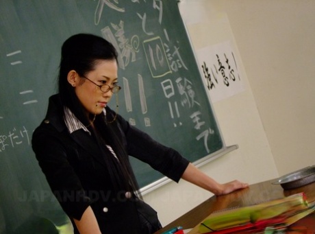 Yui Komine, a hot and humid Asian teacher, engages in kneeling and sucking a few dicks in a classroom.