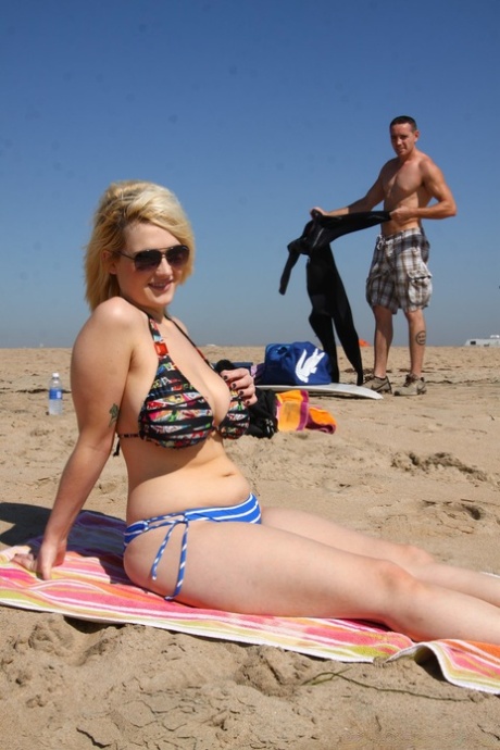 While lounging on the beach, slender blonde Siri flaunts her ample bikinis.