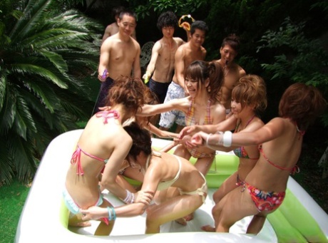 Japanese young women in thongs are seen enjoying themselves in a small outdoor swimming pool.