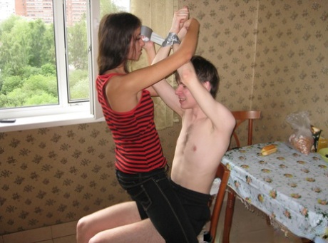 The stud-wielding Dusya of Kinky's girlfriend is being observed by her gagged BF who watches.