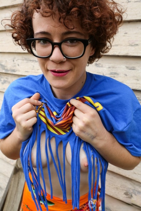 Rosie Budd, a curly haired nerd, strips and displays her erect nipples.