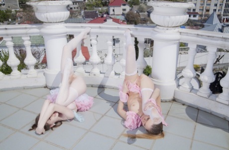 On a terrace, Emily Bloom & Katie A showcase their tiny stomachs and buttocks.