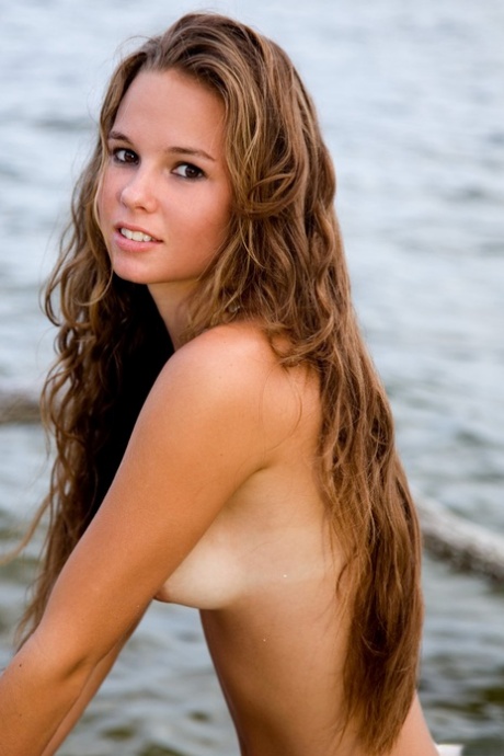 Glamorous teen Aria A	displays her hot body with tan lines on the beach