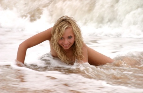 Blonde teen Alena A teases with her natural breasts and poses on the beach
