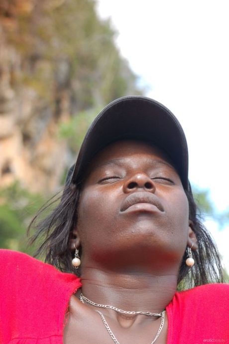 Exhibiting her ass in the air, Ebony Maria L removes all of her clothing except for her shorts and red shirt.