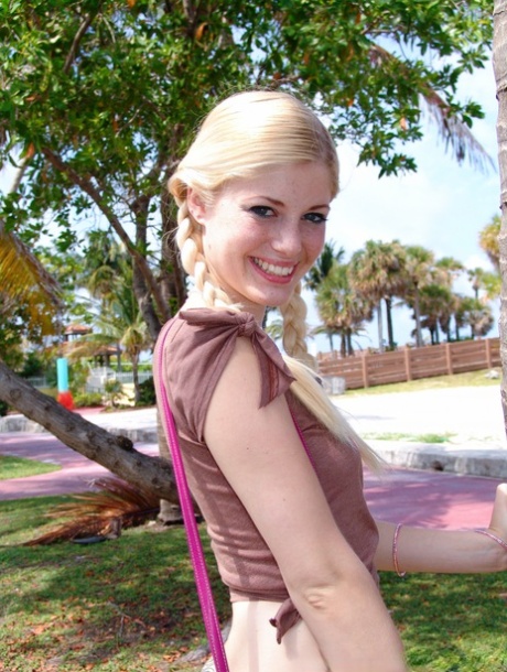 Petite blonde Charlotte Stokely posing by a big palm tree in public