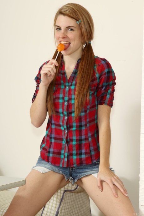 With an orange lollipop in hand, Aubrey Belle (the kitty) masturbates while wearing a plaid shirt.