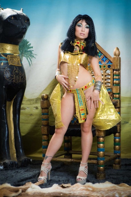Dressed as Cleopatra, Petite Asian Rina Ellis displays her chest and buttocks.