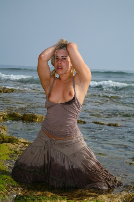 On a sandy beach, Tammy Oldham from Britain poses for photos while she masturbates.