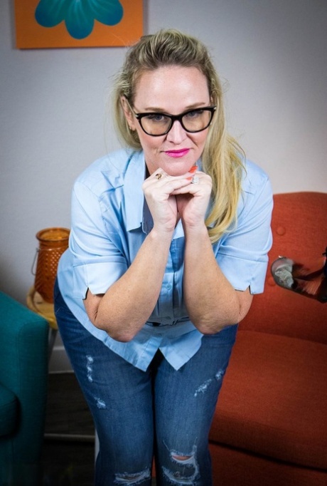 In a pair of hot jeans and a blue shirt, Dee Siren appears as a naughty blonde with glasses.