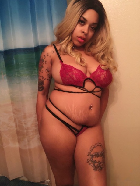 Soykay Linda, the solo artist, displays her large buttocks and a tattooed chest while wearing an ebony blonde.