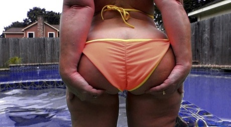 Sexy PAWG member Dee Siren in her orange bikini by the pool.
