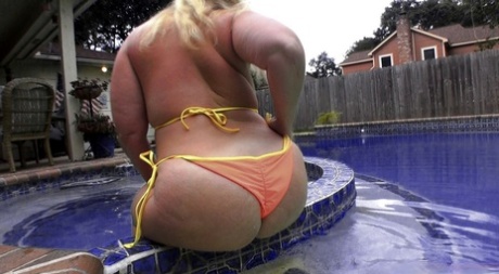 Sexy PAWG member Dee Siren in her orange bikini by the pool.