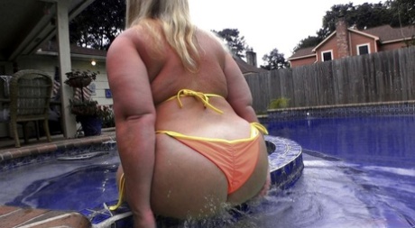 Sexy: Older PAWG member Dee Siren poses in her orange bikini by the pool.