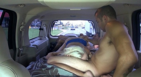 In the van 3some, Dee Siren, a full-figured blonde MILF, exposes her breasts and engages in sexual activity.