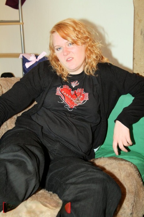 She strips her sweatshirt and exposes her belly with a black bra, being the redheaded fat.