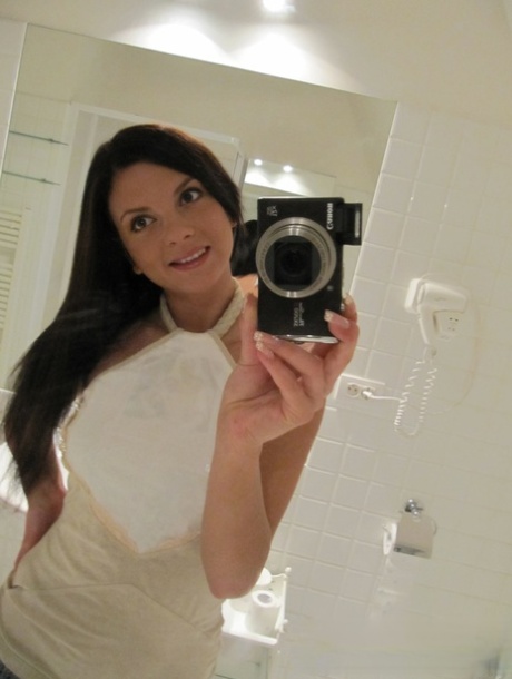 In the bathroom, the sexy babe takes selfies with her big tits and strips off in her clothes.