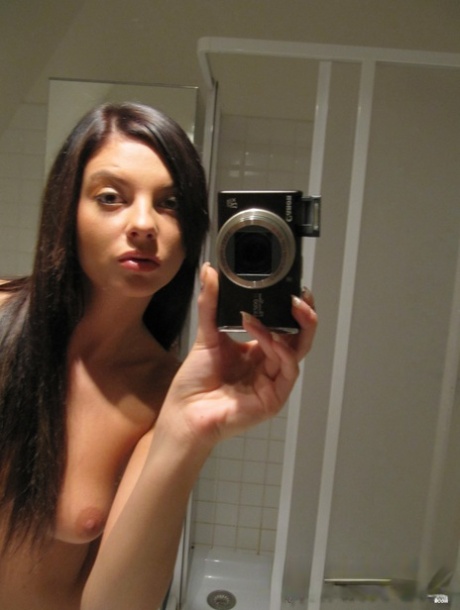 Comely babe strips nude while taking selfies of her big tits in the bathroom