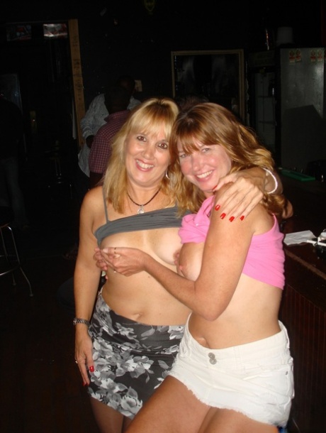 At a party, double digits blonde friend kisses Amateur Double Dee while showing off her large breasts.