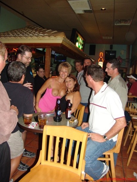 Serious wives exhibit their full chests while partying at the bar.