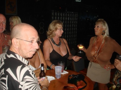 Demonstrating her massive breasts, amateur swingers throw a wild party at the bar.