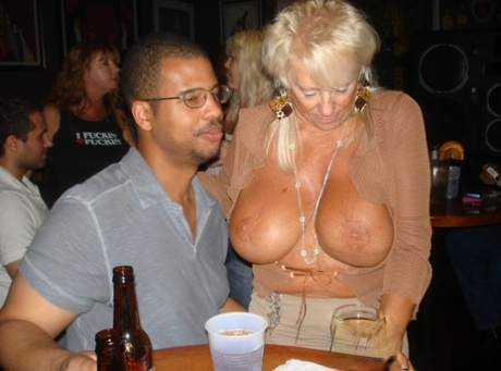 The big boobs of the woman are showcased by amateur swingers during a wild celebration at the bar.