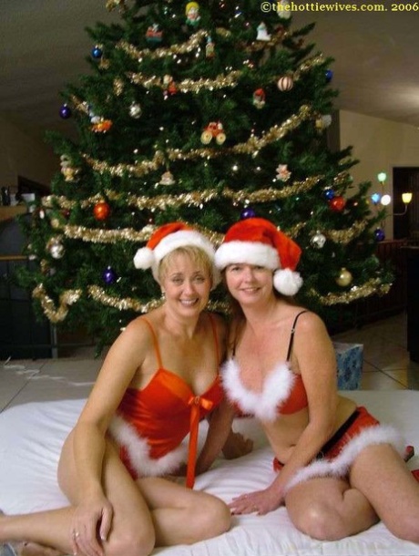 In their Xmas attire, amateur swingers enjoy playing in front of a Christmas tree.