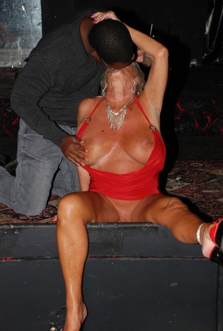 Tracy Lick, a tall blonde and mature swinger, is seen with a black cock in her mouth while partying.