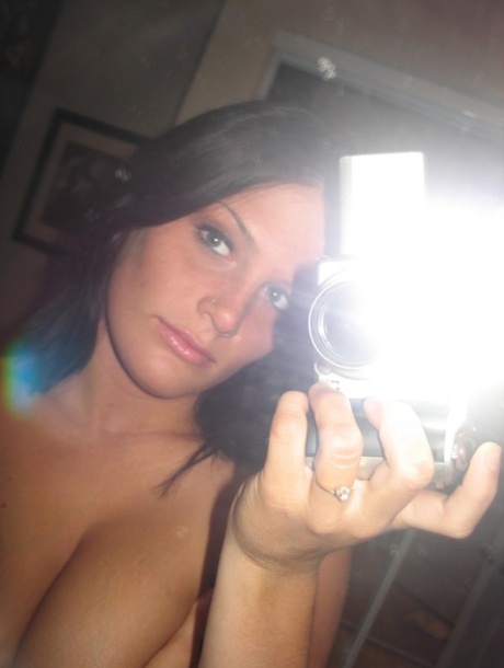 A brunette amateur displays her prominent breasts during a nude photo shoot.