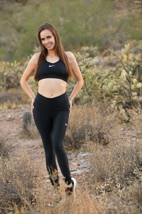 While doing exercises outside, Madi, a young and talented female athlete, displays her bellies and buttocks.