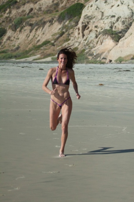 Сексуальная натуральная зрелая Софи Мари бегает по пляжу в очень скудном бикини