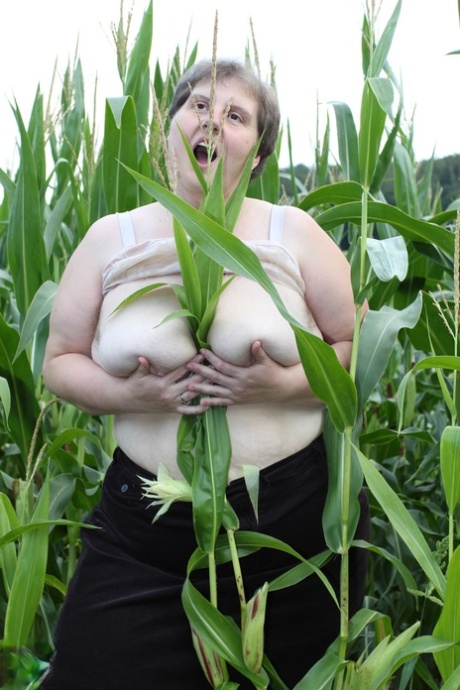 In a corn field, Tina C the plump European takes off her clothes and masturbates while fully clothed.