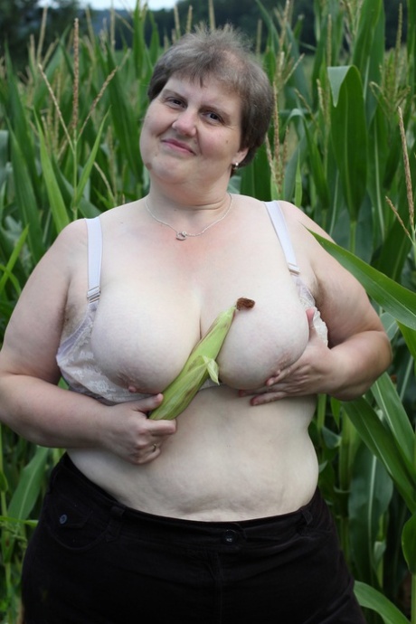 Tina C, a plump European, takes on a masturbation pose while undressing in a corn field.