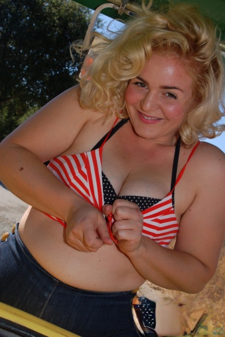 Poppy Cox, a slender blonde, sews up on a tractor and displays her curves and curvy hair.