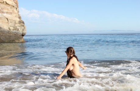 Maggie Mayhem, a novice at heart, teases with her big tits while lounging on the beach.