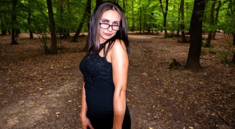 Looking sharp, Anna wears glasses and displays her ample boobs while playing in the woods.