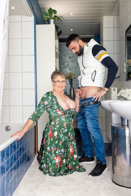 A young dick is fucked by Petra, the short-haired grandmother who wears eyeglasses, while she plays with him in the bathroom.