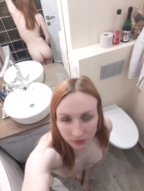 The amateur ginger appearing slim in the mirror, with small but prominent breasts and slender build.