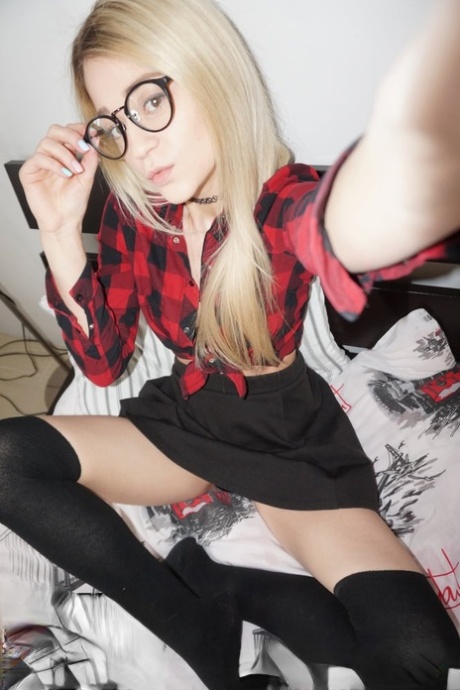 A young amateur with glasses and blonde hair sheds her attire and captures seductive selfies.