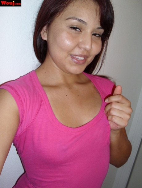 A sexy Asian female displays her large buttocks while wearing a pink shirt and no bra.