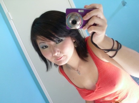 An amateur, Asian female with large breasts takes stunning selfies in front of the mirror.